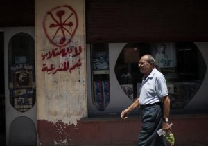 An Egyptian man walks in front of a pharmacy marked with anti-Coptic and anti-coup graffiti in Assiut, Upper Egypt.(Photo: Manu Brabo, AP)