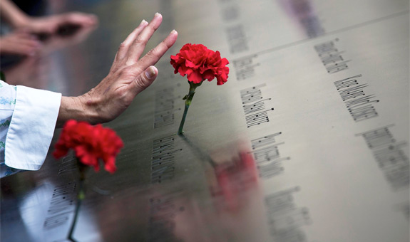 A woman touches a carnation left on a name inscribed into the North Pool during 9/11 memorial ceremonies marking the 12th anniversary of the Sept. 11, 2001, terrorist attacks on the World Trade Center in New York. The attacks claimed the lives of nearly 3,000 people in New York City, Shanksville, Pa., and at the Pentagon.(CNS photo/Adrees Latif, Reuters)