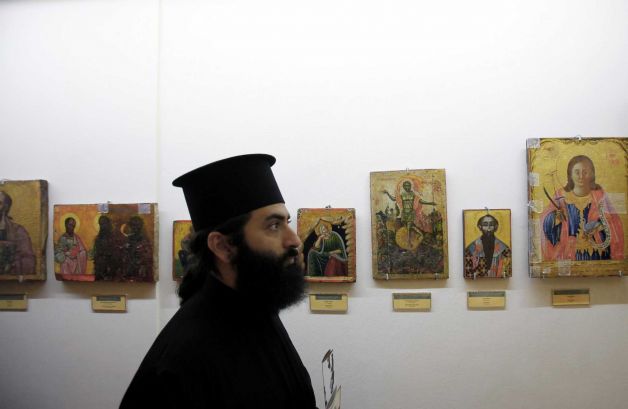 A man use his mobile to take a photo of the 14th century icon of the Virgin Mary, or Panayia, the Merciful after returned looted icons at the Byzantine Museum in capital Nicosia, Cyprus, Tuesday, Nov. 12, 2013. 