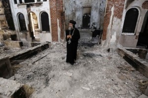 A Coptic Orthodox bishop surveys a damaged church in Minya, Egypt last year (CNS) 