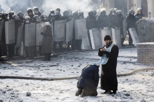 KIEV, UKRAINE - JANUARY 25: A man kneels before an Orthodox priest in an area separating police and anti-government protestors near Dynamo Stadium on January 25, 2014 in Kiev, Ukraine. Violent protests in Ukraine have spread beyond the capital as President Viktor Yanukovych held crisis talks with three key opposition leaders. (Photo by Rob Stothard/Getty Images)