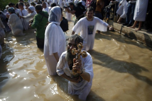 A Christian pilgrim holds a cross as he dips in the water after a ceremony at the baptismal site known as Qasr el-Yahud on the banks of the Jordan River near the West Bank city of Jericho January 18, 2015. (Reuters/Mohamad Torokman)