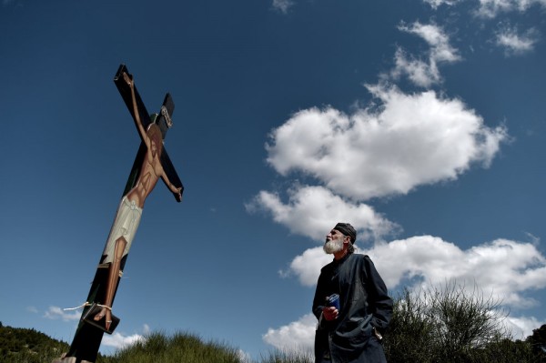 A monk of the Greek Orthodox Church looks at an image of Jesus crucified, during the ceremony marking the Apokathelosis, the removal of Christ's dead body from the Cross, which forms a key part of Orthodox Easter, at the Church of the Dormition of the Virgin in Penteli, north Athens on April 10, 2015.