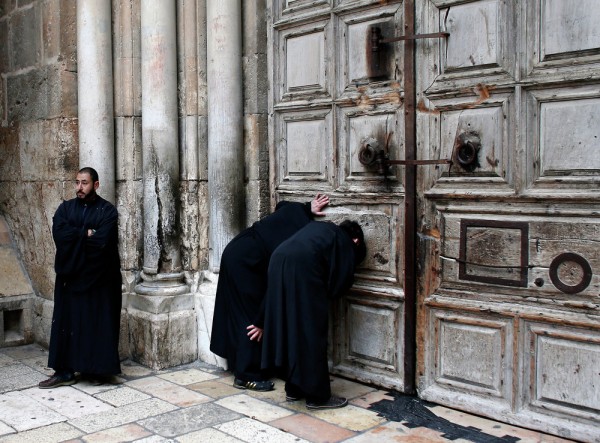 Christian Orthodox priests look through a hole in the main door of the Church of the Holy Sepulchre, before the Holy Fire ceremony around Jesus' tomb, in Jerusalem’s Old City. April 11, 2015.