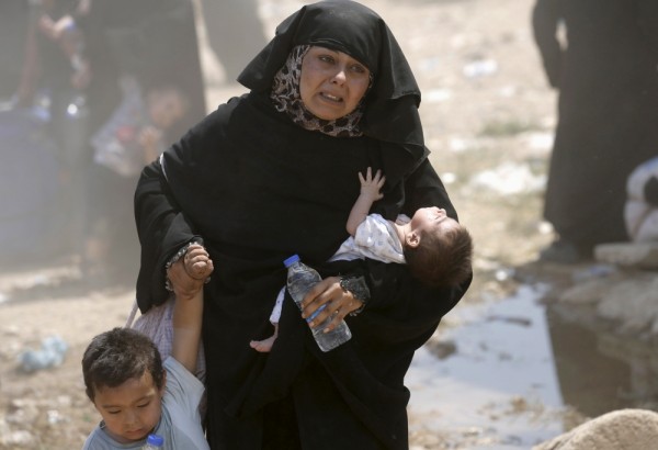 PHOTO: REUTERS/UMIT BEKTAS. A Syrian refugee woman crosses into Turkey with her children at the Akcakale border gate in Sanliurfa province, Turkey, June 15, 2015.