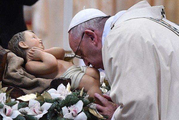 Pope Francis kisses a statue of Baby Jesus during the Epiphany mass at St Peter's Basilica in the Vatican Gabriel Bouys/AFP