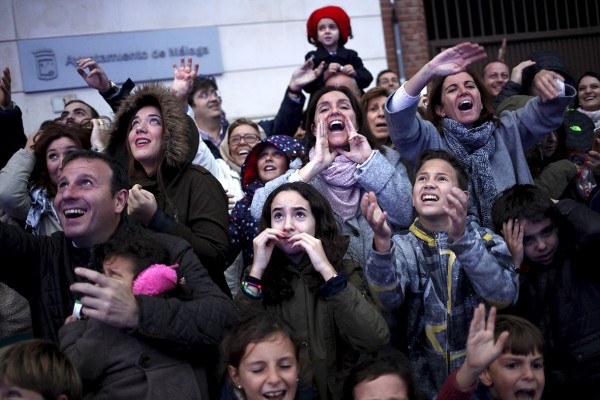 People react as sweets are thrown to them from a float by actors dressed as the Three Wise Men during the traditional Epiphany parade in Malaga, southern Spain Jon Nazca/Reuters