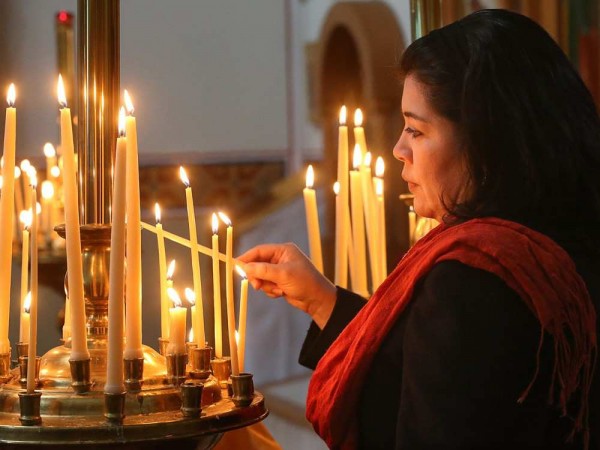 Parishioner Marta Santanilla lights a candle for the living in front of the church altar. JULIE OLIVER / OTTAWA CITIZEN