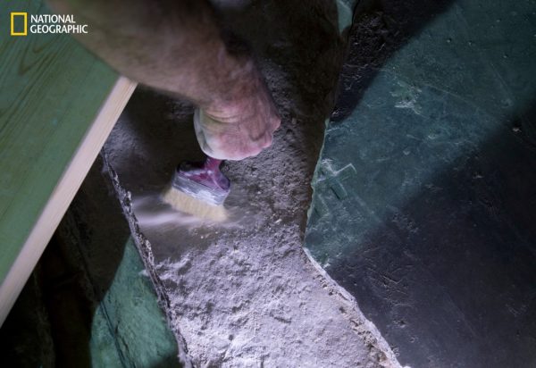 An expert carefully brushes away loose dust and dirt from the original limestone that’s said to be the tomb of Jesus Christ. The small cross was etched during the Crusades. Credit: ODED BALILTY / NATIONAL GEOGRAPHIC